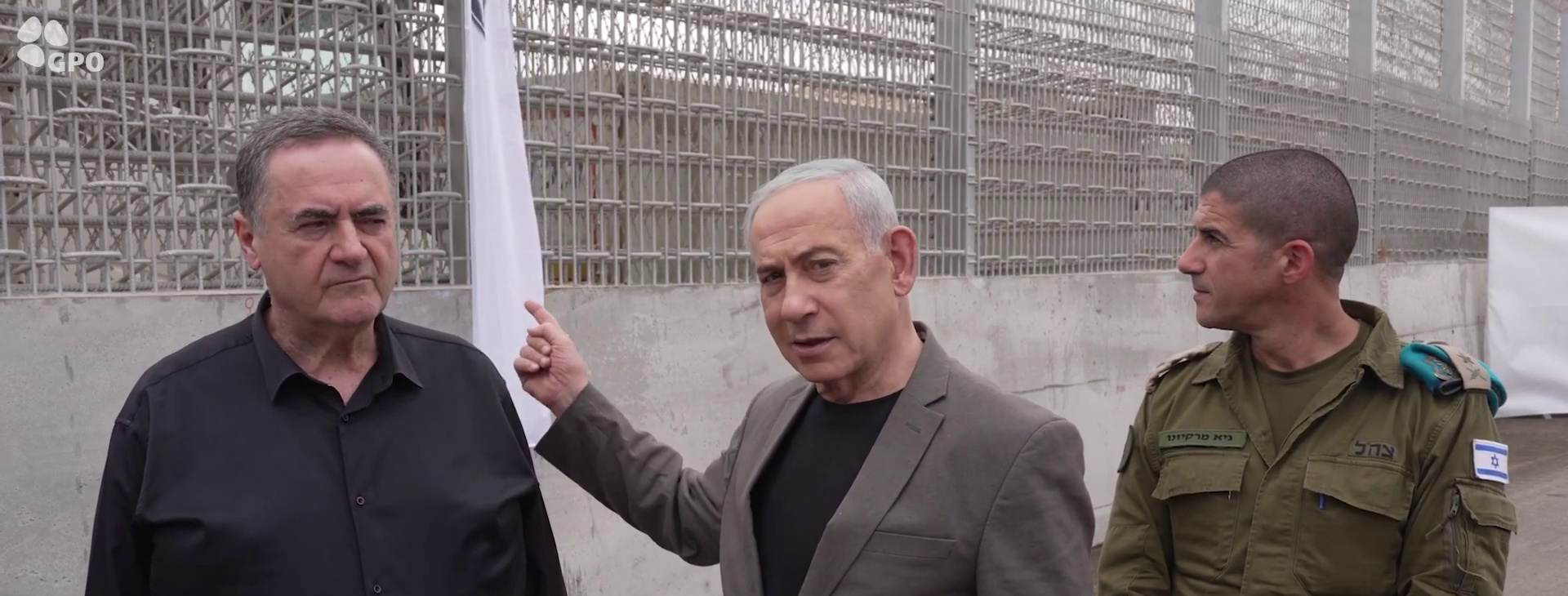 Netanyahu, center, points toward the barrier as Defense Minister Israel Katz, left, and an IDF officer look on near Kibbutz Massada.